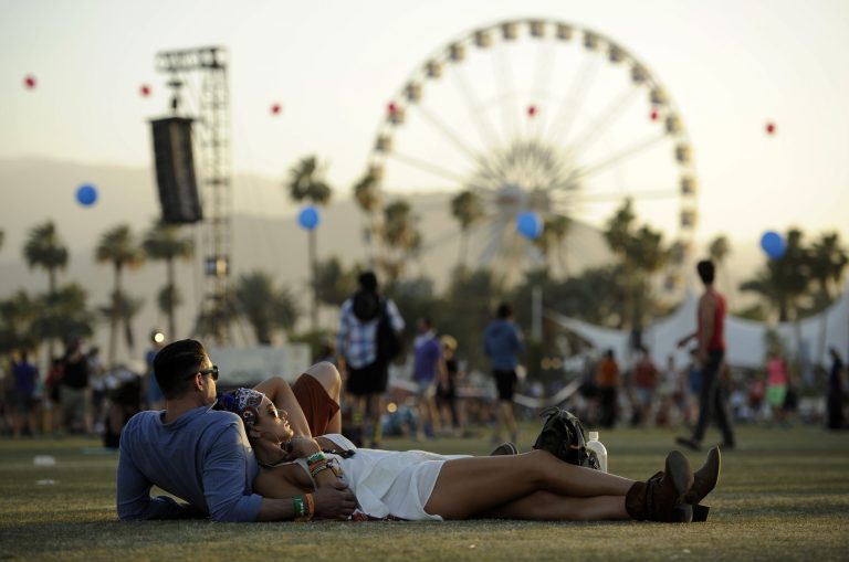 FILE - In this Sunday, April 13, 2014 file photo, Coachella festival goers Justin Gibbs and Olivia Hansen of Los Angeles relax on the Empire Polo Field during the third day of the 2014 Coachella Music and Arts Festival in Indio, Calif.  The Coachella crowd may be there to listen to music under the hot desert sun, but the retailers are there for the celebs and the crowd, which is young, hip and with money to spend.  (Photo by Chris Pizzello/Invision/AP, file)
