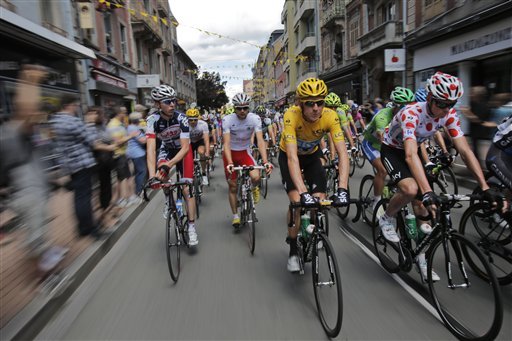 Bradley Wiggins of Britain, wearing the overall leader's yellow jersey, Ryder Hesjedal of Canada, wearing the best young rider's white jersey, and Christopher Froome of Britain, wearing the best climber's dotted jersey, ride in the pack during the start of the 8th stage of the Tour de France cycling race over 157.5 kilometers (98.5 miles) with start in Belfort, France, and finish in Porrentruy, Switzerland, Sunday July 8, 2012. (AP Photo/Christophe Ena)