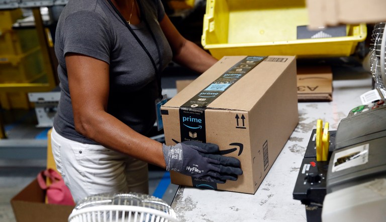FILE- In this Aug. 3, 2017, file photo, Myrtice Harris applies tape to a package before shipment at an Amazon fulfillment center in Baltimore. Amazonâs announced Tuesday, Oct. 2, 2018, that it would raise its hourly minimum wage to $15. Those who already made $15 will get an extra dollar an hour when the change is made next month, but they will also lose two benefits they relied on: monthly bonuses that could top hundreds of dollars and a chance to own Amazonâs sky-rocketing stock, currently worth nearly $2,000.