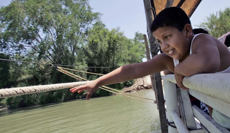 Joe Cardenas, 9, reaches for the rope used to pull the hand drawn ferry between the U.S. and Mexico border at Los Ebanos, Texas, Wednesday, Aug. 8, 2007.