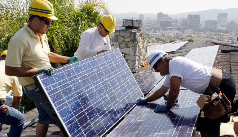 Installers from California Green Design install solar electrical panels on the roof of a home in Glendale, Calif.