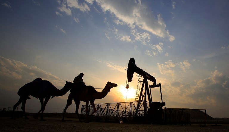 In this Dec. 20, 2015, file photo, a man rides a camel through the desert oil field and winter camping area of Sakhir, Bahrain.