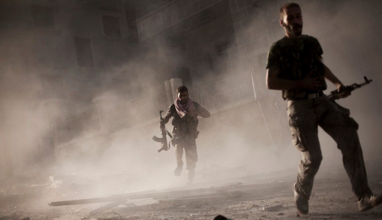 Free Syrian Army fighters run away after attacking a Syrian Army tank during fighting in the Izaa district in Aleppo, Syria, Friday, Sept. 7, 2012.