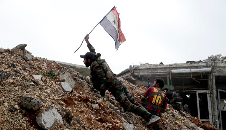 A Syrian army soldier places a Syrian national flag during a battle with rebel fighters at the Ramouseh front line, east of Aleppo, Syria, Monday, Dec. 5, 2016. The government seized large swathes of the Aleppo enclave under rebel control since 2012 in the offensive that began last week. The fighting was most intense Monday near the dividing line between east and west Aleppo as government and allied troops push their way from the eastern flank, reaching within less than a kilometer (half a mile) from the citadel that anchors the center of the city.