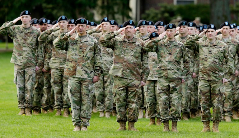 U.S. Army soldiers salute as they stand in formation during a ceremony.