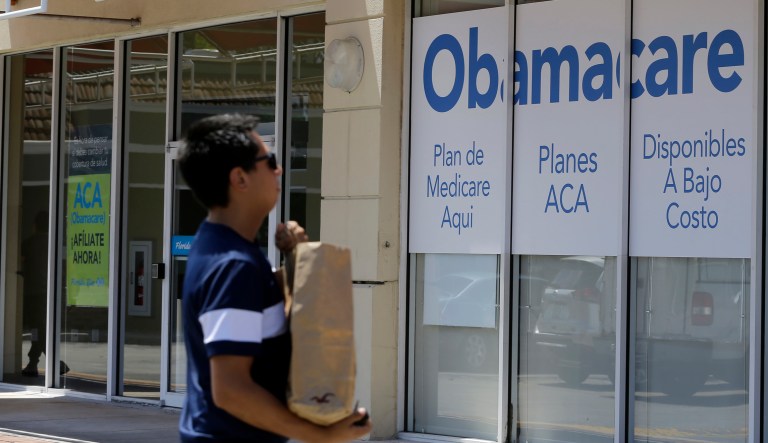 This photo taken Thursday, July 27, 2017, shows a man walks by an healthcare insurance office in Hialeah, Fla. 