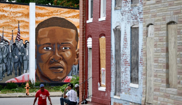 A mural depicting Freddie Gray is seen past blighted row homes in Baltimore, at the intersection where Gray was arrested.