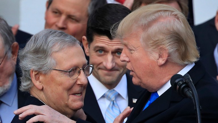 President Donald Trump congratulates Senate Majority Leader Mitch McConnell of Ky., while House Speaker Paul Ryan of Wis., watches to acknowledge the final passage of tax overhaul legislation by Congress at the White House in Washington, Wednesday, Dec. 20, 2017.