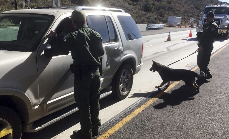In this Dec. 14, 2017 photo, border patrol agents use a drug sniffing dog to check vehicles in California. 