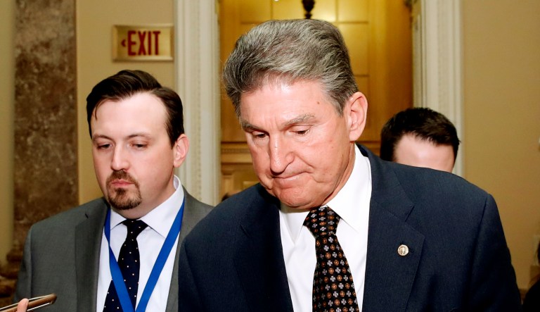 Sen. Joe Manchin (pictured center-right), D-W.Va., walks with reporters on Capitol Hill in Washington, D.C.