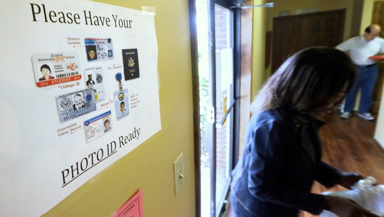 An election worker walks past a voter ID sign at a Little Rock, Ark., polling place.