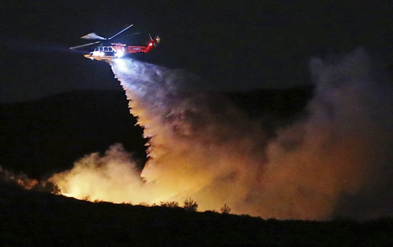 A helicopter makes a water drop on a brush fire that broke out near Temescal Ridge Trail in the vicinity of Skull Rock in a remote section of Topanga State Park in the hills above the Pacific Palisades neighborhood of Los Angeles Wednesday evening, Feb. 21, 2018. No structures are threatened and no evacuations have been called for.