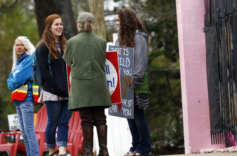 Clinic escort Derenda Hancock, left, stands near anti-abortion sidewalk counselors as they stand outside the Jackson Women's Health Organization's clinic, the only facility in the state that performs abortions, Tuesday, March 20, 2018 in Jackson, Miss.
