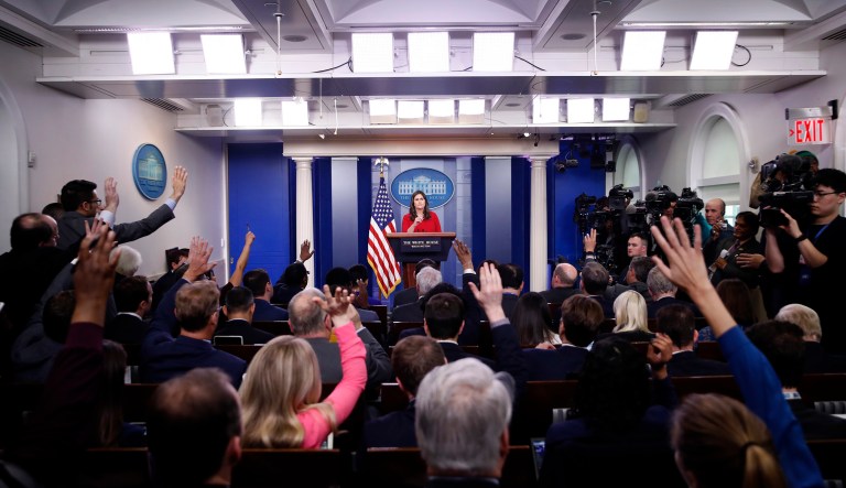 Reporters raise their hands to ask a question of White House press secretary Sarah Sanders. 