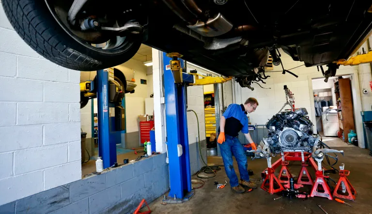 In this photo made on Thursday, April 26, 2018, automotive technicians Ian West inspects the under carriage of a car after the engine and transmission assembly was removed at a repair shop in Harmony, Pa. 