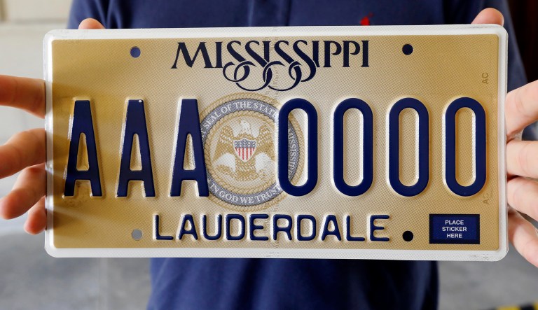 Clay Chandler, director of communications for Gov. Phil Bryant, holds Mississippi's new standard license plate Thursday, May 10, 2018, at the Capitol in Jackson, Miss. It will display the state seal that includes the phrase, "In God We Trust." Republican Gov. Bryant unveiled the new design on Twitter. It will be available beginning in January 2019.