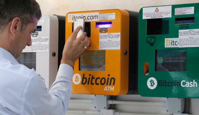 A man uses the Bitcoin ATM in Hong Kong, Friday, May 11, 2018. Bitcoin is the world's most popular virtual currency. Such currencies are not tied to a bank or government and allow users to spend money anonymously.