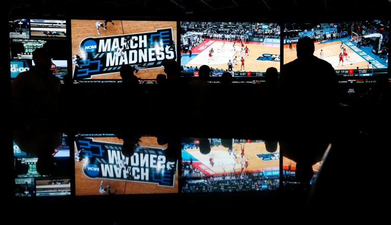 In this March 15, 2018 photo, people watch coverage of the first round of the NCAA college basketball tournament at the Westgate Superbook sports book in Las Vegas. The Supreme Court has struck down a federal law that bars gambling on football, basketball, baseball and other sports in most states, giving states the go-ahead to legalize betting on sports.   (AP Photo/John Locher)