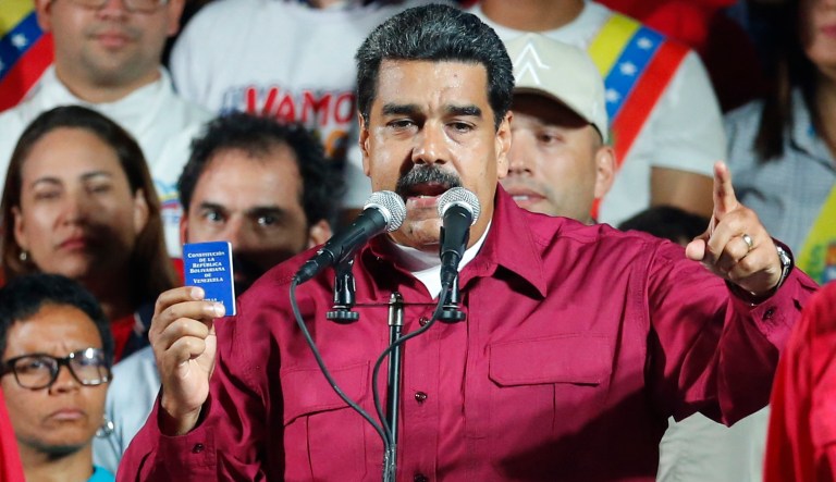 Venezuela's President Nicolas Maduro, holding a copy of the country's constitution, addresses supporters at the presidential palace in Caracas, Venezuela, after electoral officials declared he was re-elected on Sunday, May 20, 2018. 