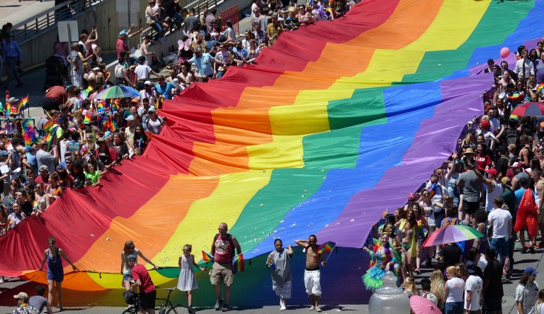 In this Sunday, June 3, 2018, photo, people carry a flag during the Utah Pride parade in Salt Lake City. Salt Lake City police are looking for leads after a man was allegedly attacked while trying to defend two gay men being chased after the Utah Pride Festival.