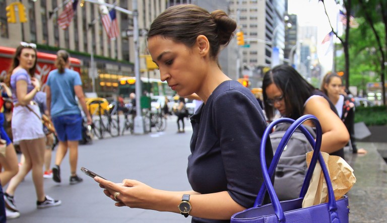 Alexandria Ocasio-Cortez, the winner of the Democratic primary victory in New York's 14th Congressional District, checks her phone during a break from press interviews in New York.