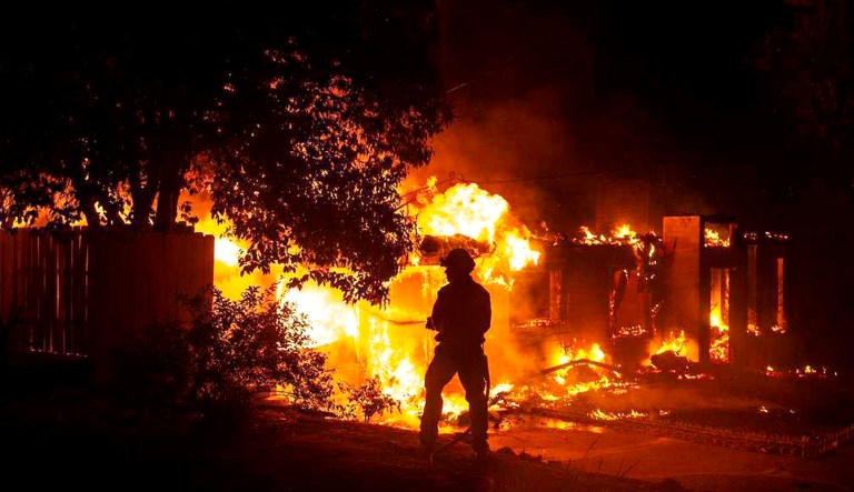 A firefighter works to battle the Carr Fire at a home in Redding, Calif., on Thursday.