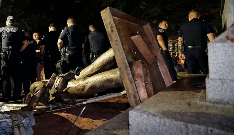 In this Monday, Aug. 20, 2018, file photo, police stand guard after the Confederate statue known as Silent Sam was toppled by protesters on campus at the University of North Carolina in Chapel Hill, N.C.