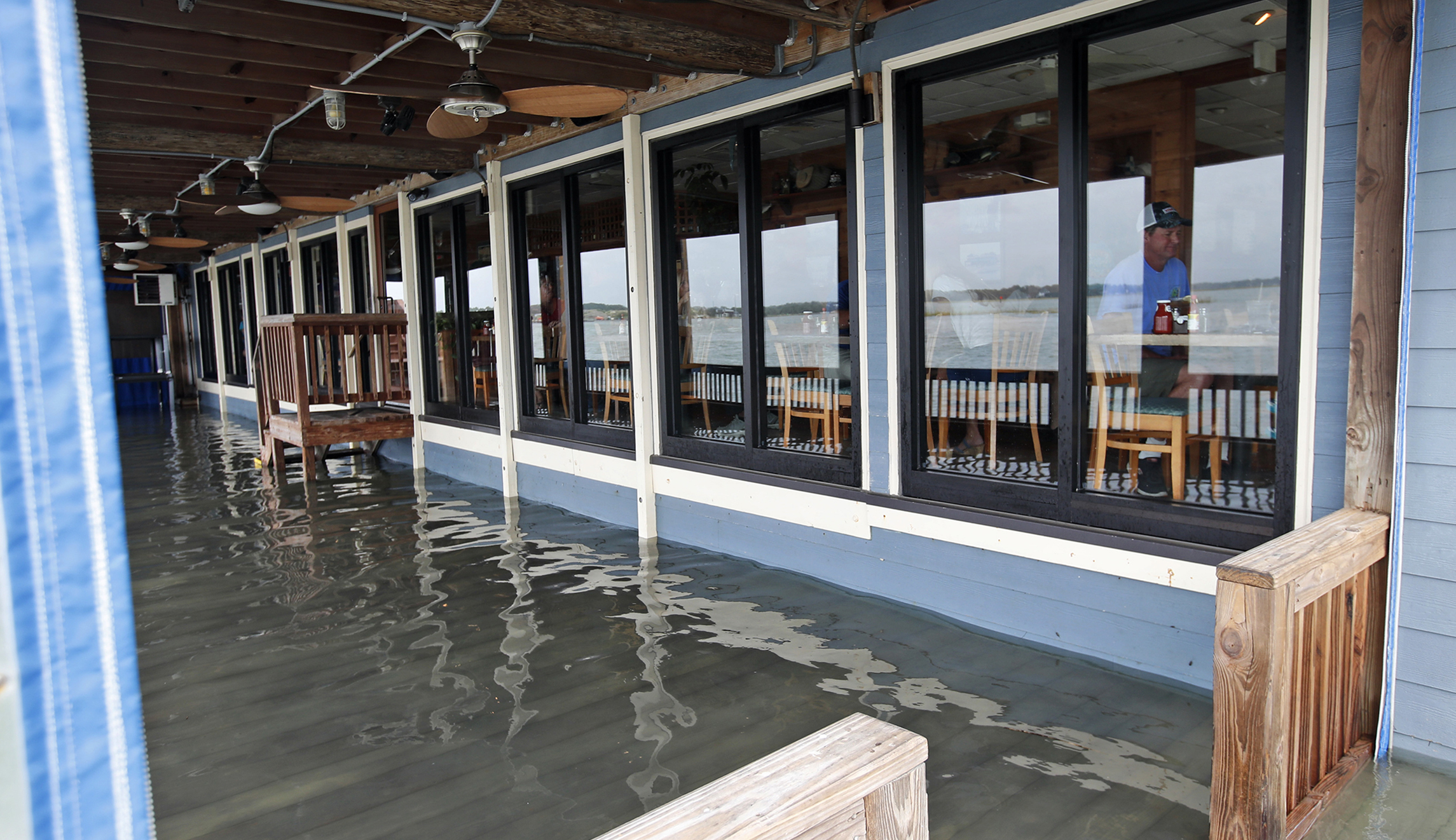 Sean Hayes, right, from Manteo, N.C., eats at Bubba's Seafood Restaurant with his family as the deck is covered with a few inches of water from effects of Hurricane Florence on Friday in Virginia Beach, Va. 