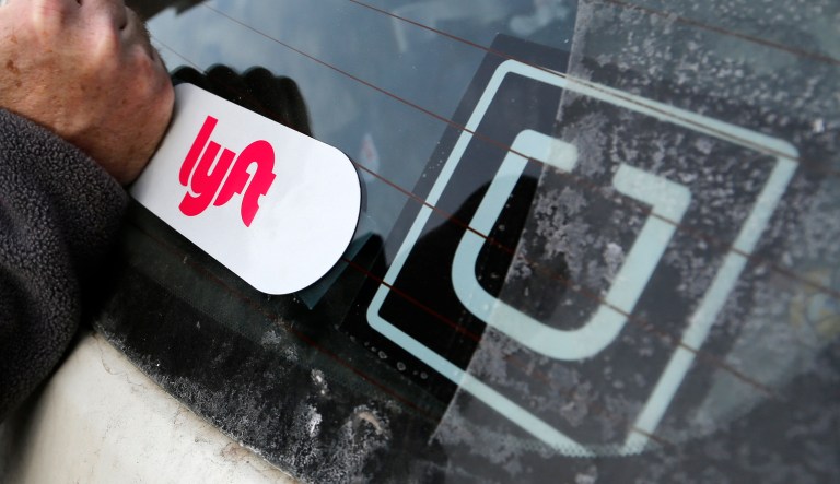 A Lyft logo is installed on a Lyft driver's car next to an Uber sticker in Pittsburgh on Jan. 31, 2018.