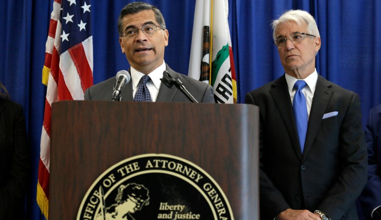 California Attorney General Xavier Becerra, left, and San Francisco District Attorney George Gascon, right, listen to questions about a settlement with Uber over a data breach during a news conference Wednesday, Sept. 26, 2018, in San Francisco. Uber will pay $148 million and tighten data security after the ride-hailing company failed for a year to notify drivers that hackers had stolen their personal information, according to a settlement announced Wednesday.