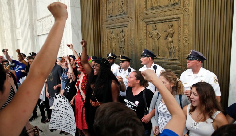 Activists protest at bronze doors of the Supreme Court after the confirmation vote of Supreme Court nominee Brett Kavanaugh, on Capitol Hill, Saturday, Oct. 6, 2018, in Washington.