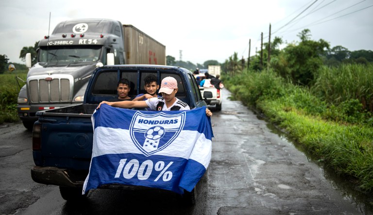 A Honduran migrant holds a Honduras national flag, as he sits in the bed of a pick-up truck, on his way to the Mexican border, in Cocales, about 80 miles north-west from Guatemala City, Guatemala. Many of the more than 2,000 Hondurans in a migrant caravan trying to wend its way to the U.S. left spontaneously with little more than the clothes on their backs and what they could quickly throw into backpacks. 