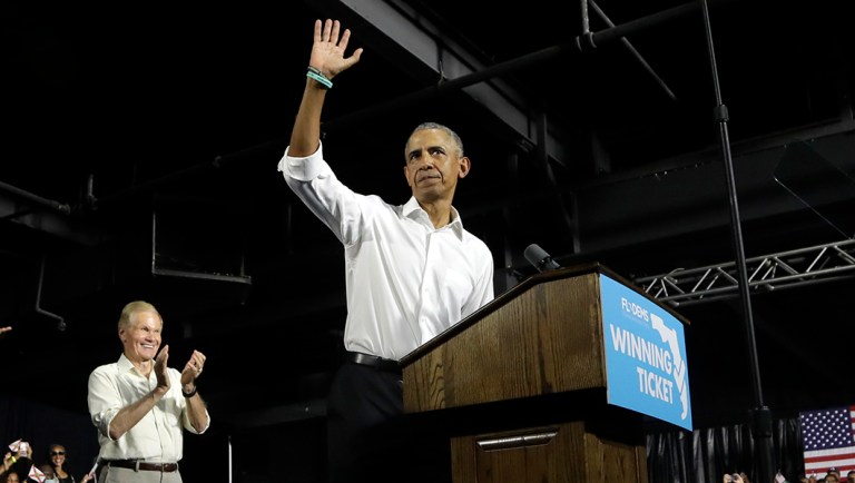 Former President Barack Obama, right, waves during a campaign rally.