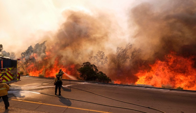 A firefighter battles a fire along the Ronald Reagan (118) Freeway in Simi Valley, Calif., Monday, Nov. 12, 2018.
