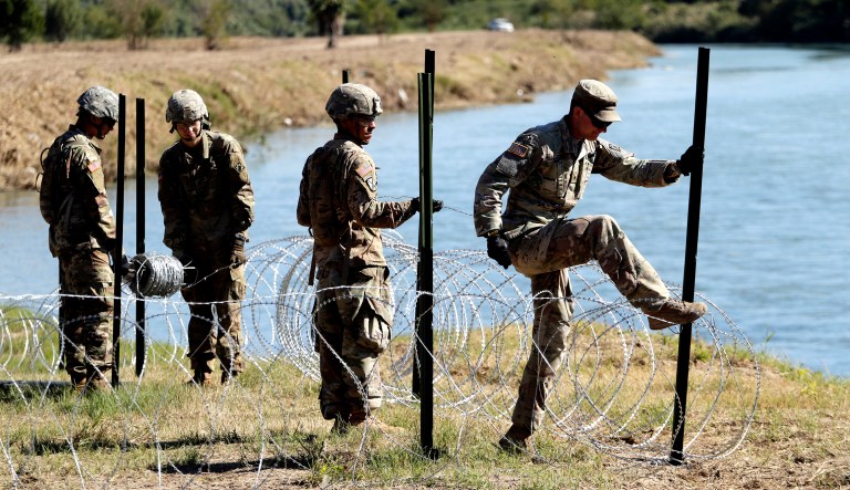 Members of the U.S. military install multiple tiers of concertina wire along the banks of the Rio Grande near the Juarez-Lincoln Bridge at the U.S.-Mexico border in Laredo, Texas. 