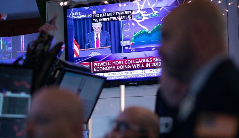 Traders at the New York Stock Exchange listen as Federal Reserve Chairman Jerome Powell is seen on a video screen giving a news conference from Washington after the Fed announced a rate increase, Wednesday, Dec. 19, 2018.