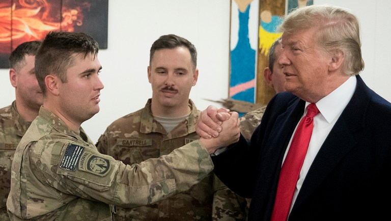 President Donald Trump shakes hands with a member of the military who said he went back into the military for President Trump, at a dining hall at Al Asad Air Base, Iraq.