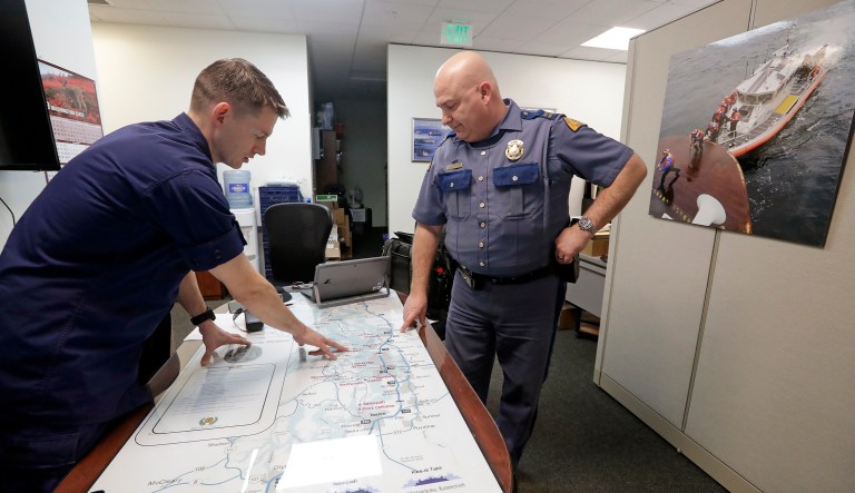 U.S. Coast Guard Lt. Cmdr. Blair Sweigert, left, who missed a paycheck a day earlier during the partial government shutdown, works with Washington State Patrol Capt. Dan Atchison in a shared office where they coordinate marine security at Sector Puget Sound base Wednesday, Jan. 16, 2019, in Seattle. The Coast Guard is part of the U.S. Department of Homeland Security, which is unfunded during the shutdown, now in its fourth week.