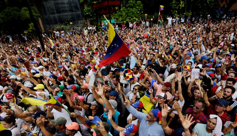 Anti-government protesters hold their hands up during the symbolic swearing-in of Juan Guaido, head of the opposition-run congress who declared himself interim president of Venezuela until elections can be called, during a rally demanding President Nicolas Maduro's resignation in Caracas, Venezuela.