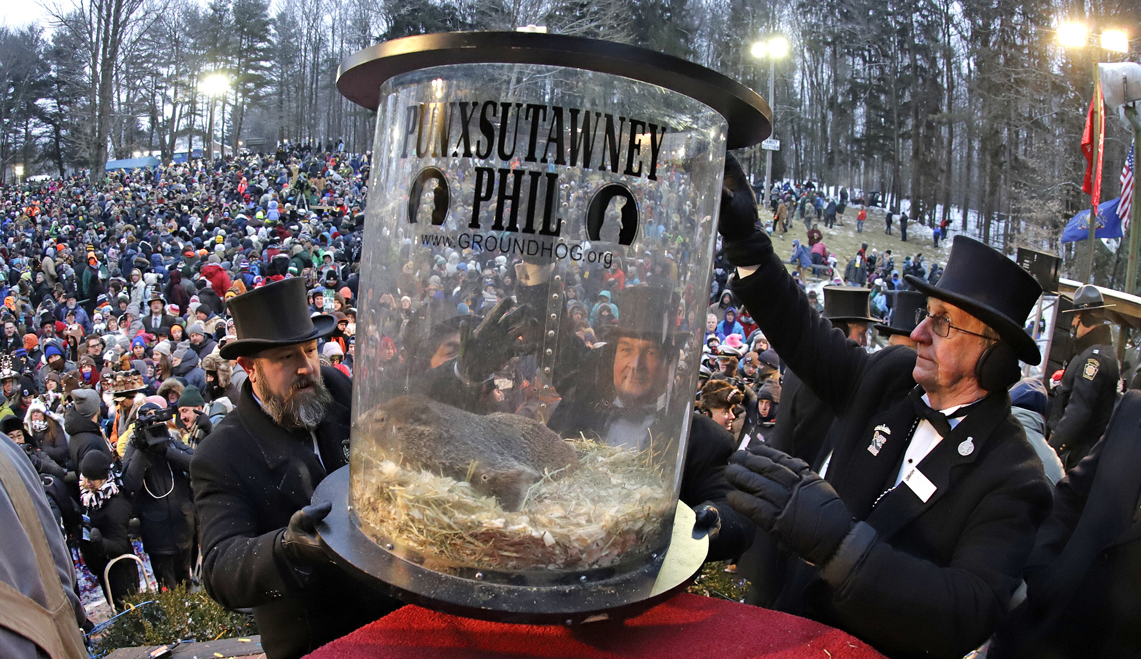 Groundhog Club co-handler Al Dereume, left, is help by Ron Ploucha, right, as they lift Punxsutawney Phil, the weather prognosticating groundhog, in his carrying capsule, during the 133rd celebration of Groundhog Day on Gobbler's Knob in Punxsutawney, Pa., on Saturday.