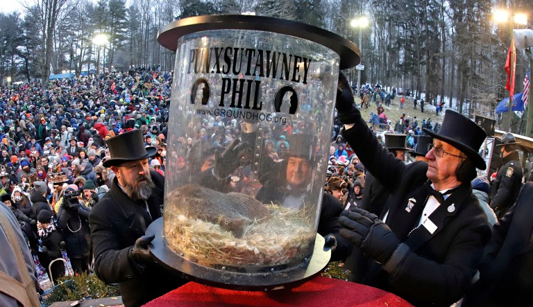 Groundhog Club co-handler Al Dereume, left, is help by Ron Ploucha, right, as they lift Punxsutawney Phil, the weather prognosticating groundhog, in his carrying capsule, during the 133rd celebration of Groundhog Day on Gobbler's Knob in Punxsutawney, Pa., on Saturday.
