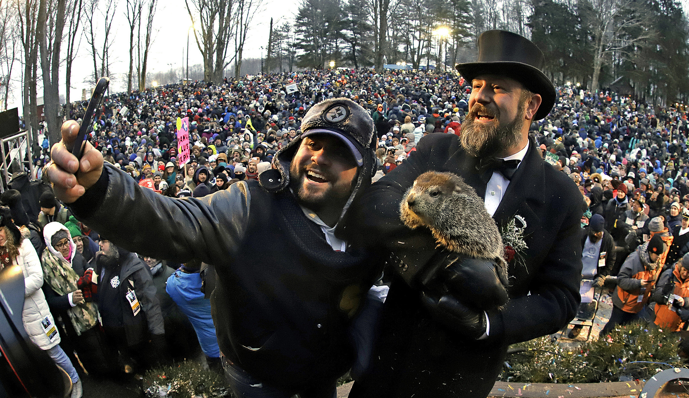 Groundhog Club co-handler Al Dereume, right, holds Punxsutawney Phil, the weather prognosticating groundhog, and poses for a selfie with a groundhog fan, in front of the crowd gathered for the 133rd celebration of Groundhog Day on Gobbler's Knob in Punxsutawney, Pa., on Saturday.