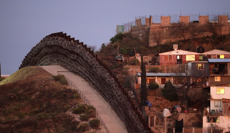 A razor-wire-covered border wall separates Nogalas, Mexico, at right, and Nogales, Ariz. at dusk Saturday, March 2, 2019. 