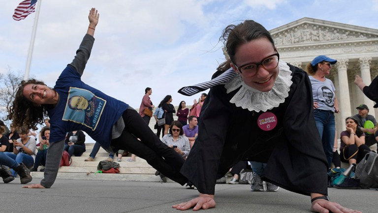 Stephanie Firestone, left, and Alice Wisbiski, right, both fans of Supreme Court Associate Justice Ruth Bader Ginsburg, do exercises on the steps of the Supreme Court in Washington.