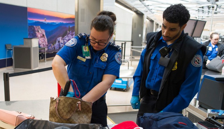 Transportation Security Administration officers search handbags which were packed in a suitcase at a checkpoint at Dulles International Airport in Dulles, Va.