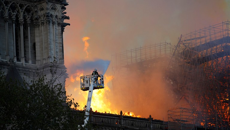 A firefighter uses a hose as Notre Dame cathedral burns in Paris.