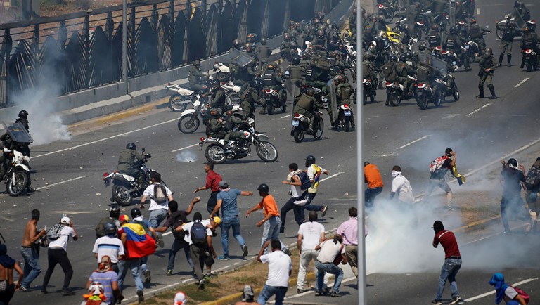 Opponents to Venezuela's President Nicolas Maduro confront loyalist Bolivarian National Guard troops firing tear gas at them.