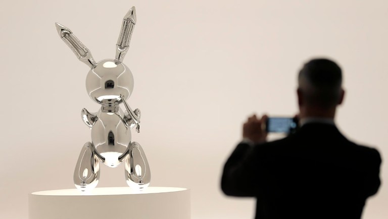 A man takes a picture of a sculpture entitled "Rabbit" by Jeff Koons during a media preview at Christie's in New York.