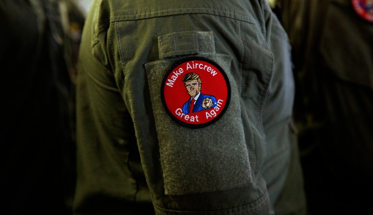 A service member wears a patch that says "Make Aircrew Great Again" as they listen to President Donald Trump speak to troops at a Memorial Day event aboard the USS Wasp, Tuesday, May 28, 2019, in Yokosuka, Japan. The patch includes a likeness of Trump.