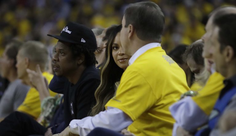 Beyonce, center, talks with Golden State Warriors owner Joe Lacob, in yellow shirt, as Jay-Z, left, looks toward the court during Game 3 of basketball's NBA Finals between the Warriors and the Toronto Raptors in Oakland, Calif., Wednesday, June 5, 2019. 